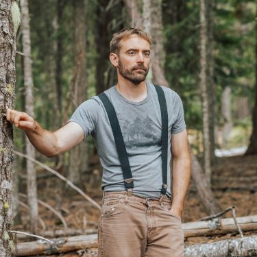 Andrew leaning up against a tree