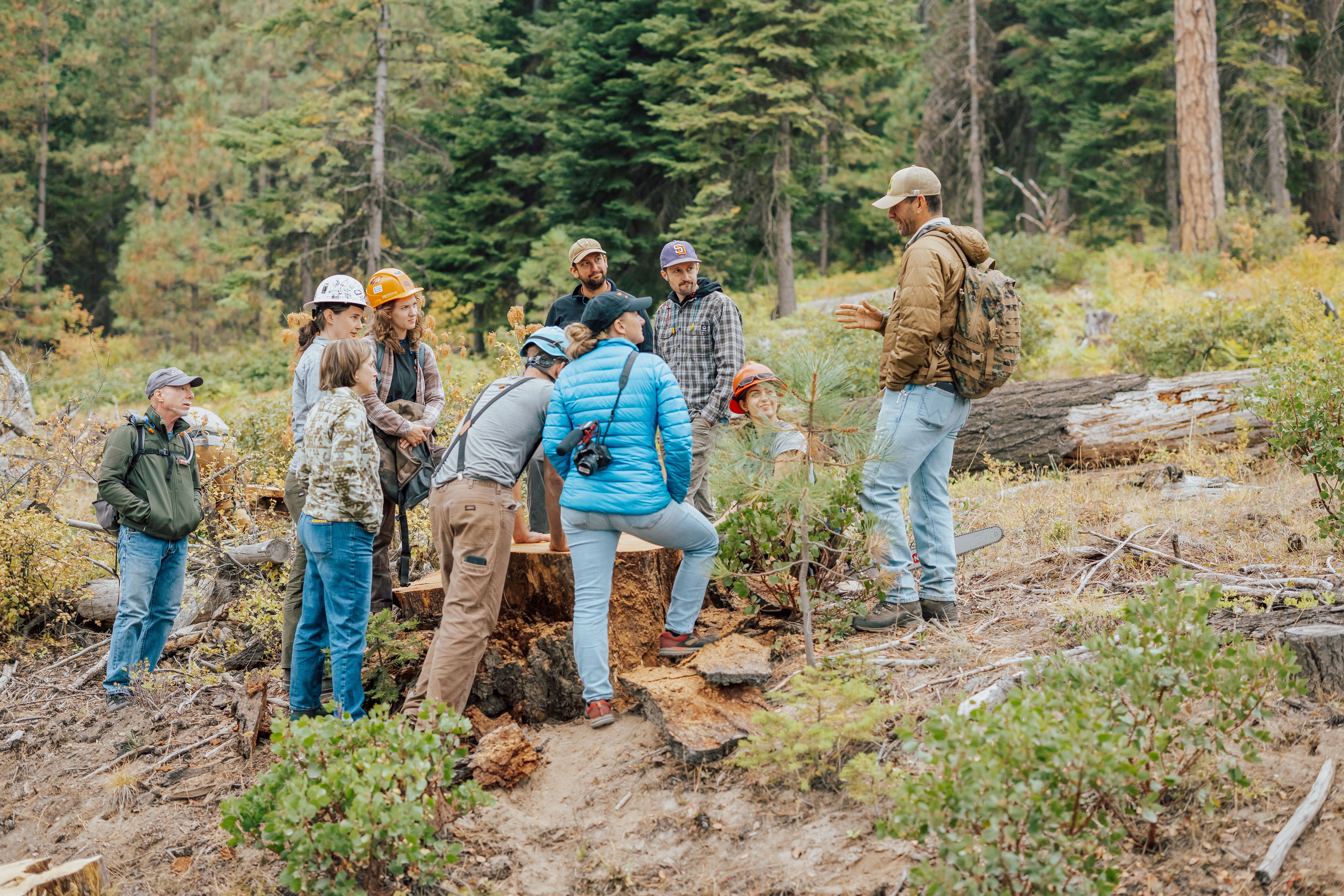 group of people gathered in the forest for a field tour